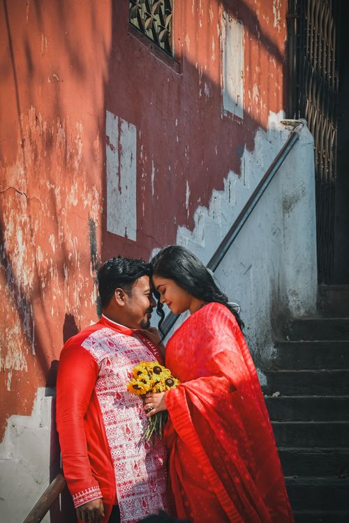 Free Couple in traditional attire shares a tender moment on a vintage stairway in Kolkata. Stock Photo