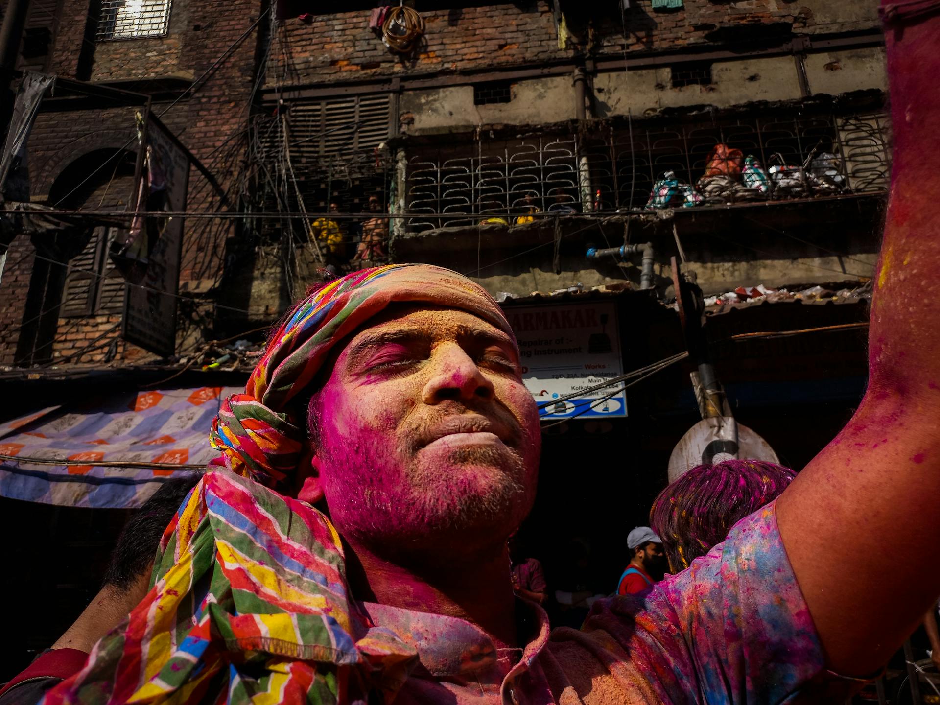 A man rejoices in vibrant colors during the Holi festival in Kolkata's busy streets.