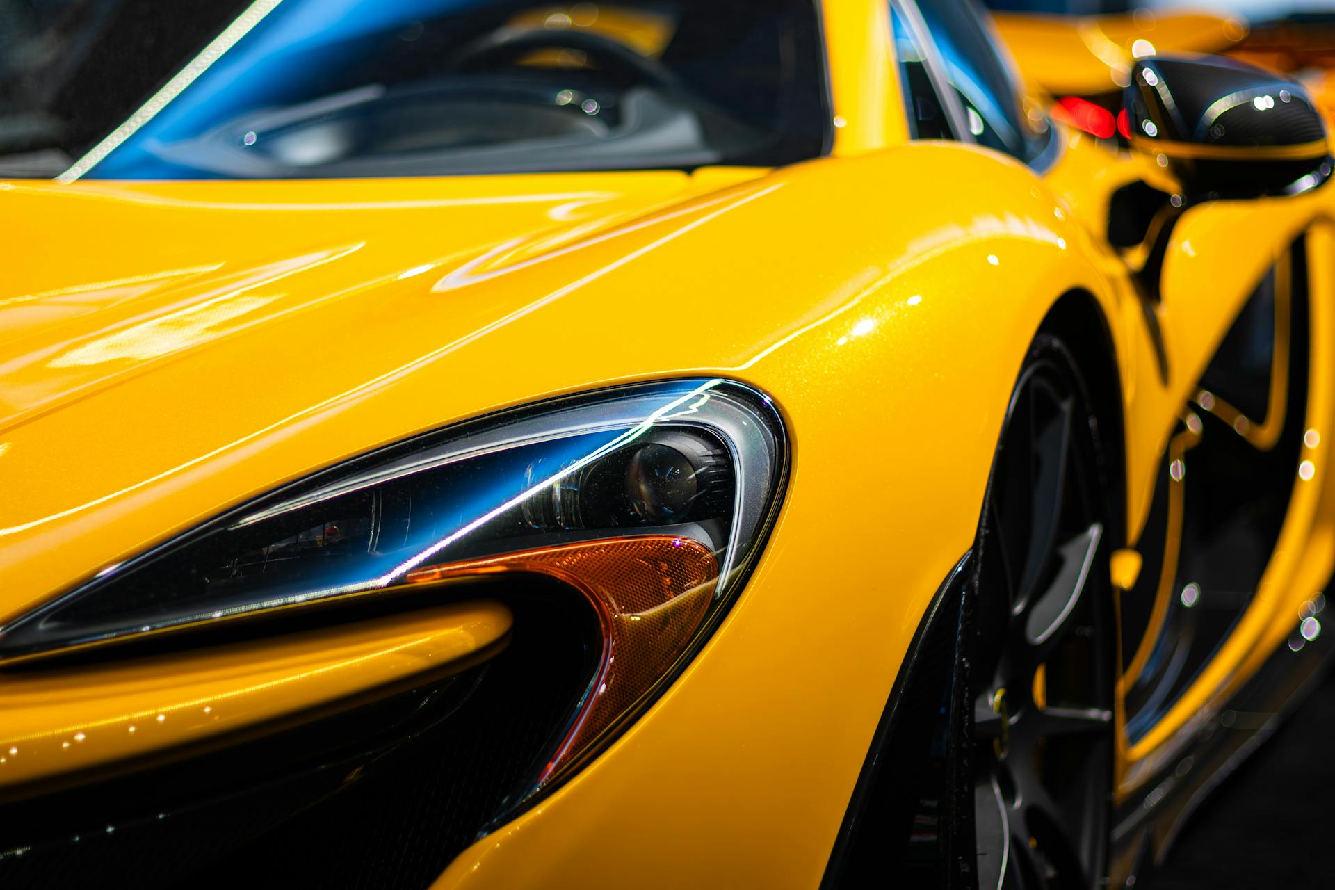 Close-up shot of a sleek yellow luxury sports car headlight, showcasing elegance and design.