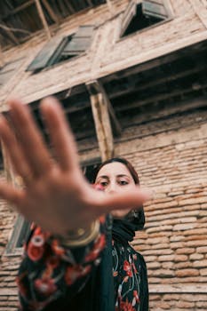 Dynamic portrait of a woman with hand extended, in front of a vintage building.