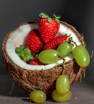 A vibrant mix of strawberries and grapes in a coconut shell, perfect for health and tropical themes.