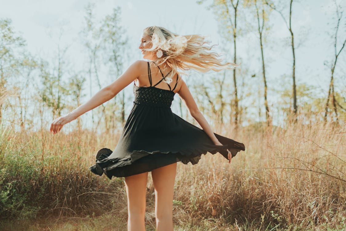 Free Back View Photo of Woman in Black Spaghetti Strap Dress Posing Stock Photo