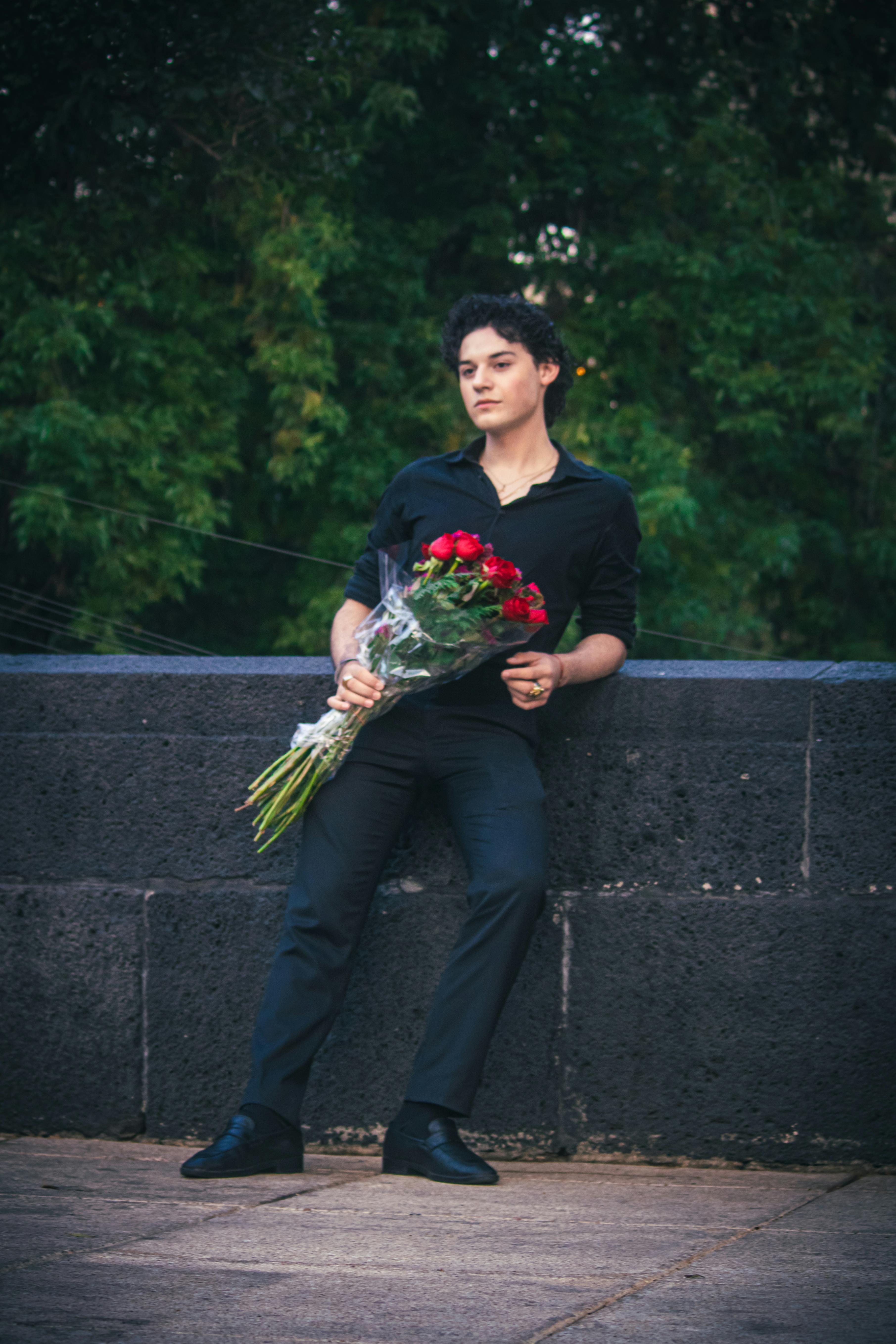Chic young man with red roses posing against a park backdrop in Ciudad de México.