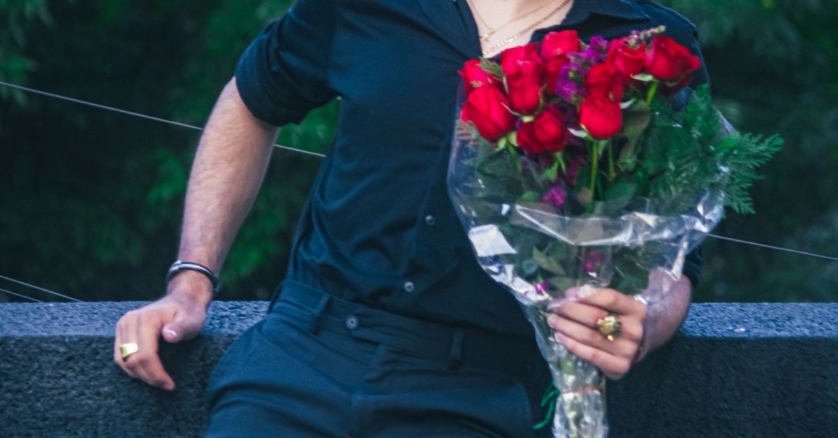 Man Among Roses Man Holding Red Roses in Urban Park Setting · Free Stock Photo