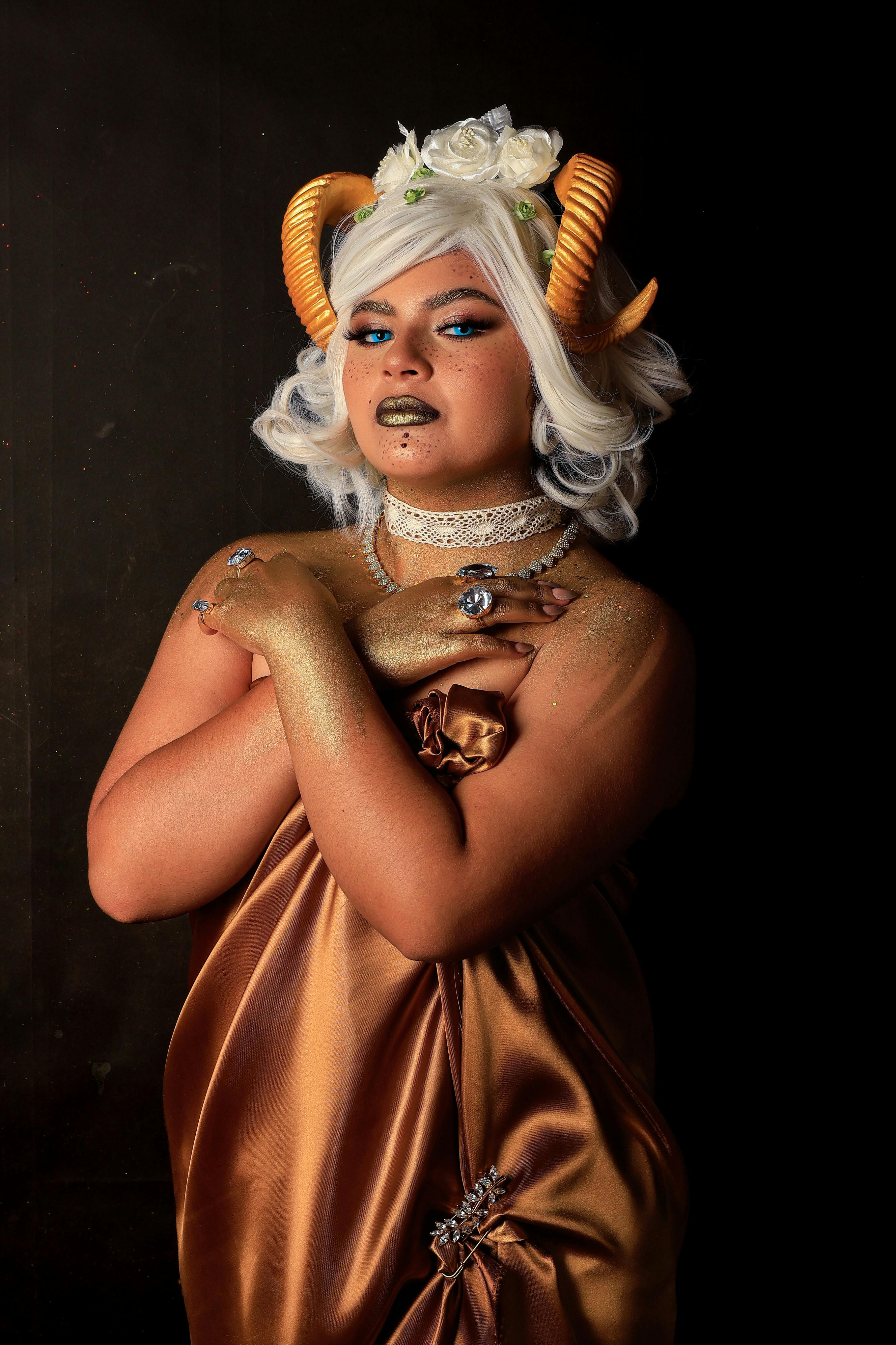 Gratuit Une personne dans un cosplay fantastique créatif avec des cornes, une tenue glamour et du maquillage sur un fond sombre. Photos
