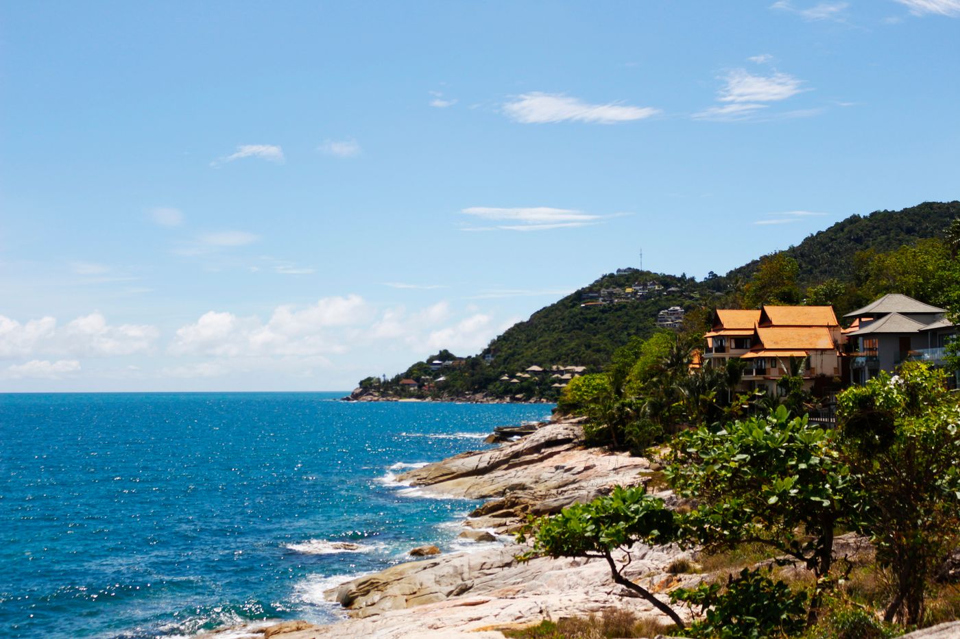 Green forested coastline of Koh Samui meeting clear blue sea.