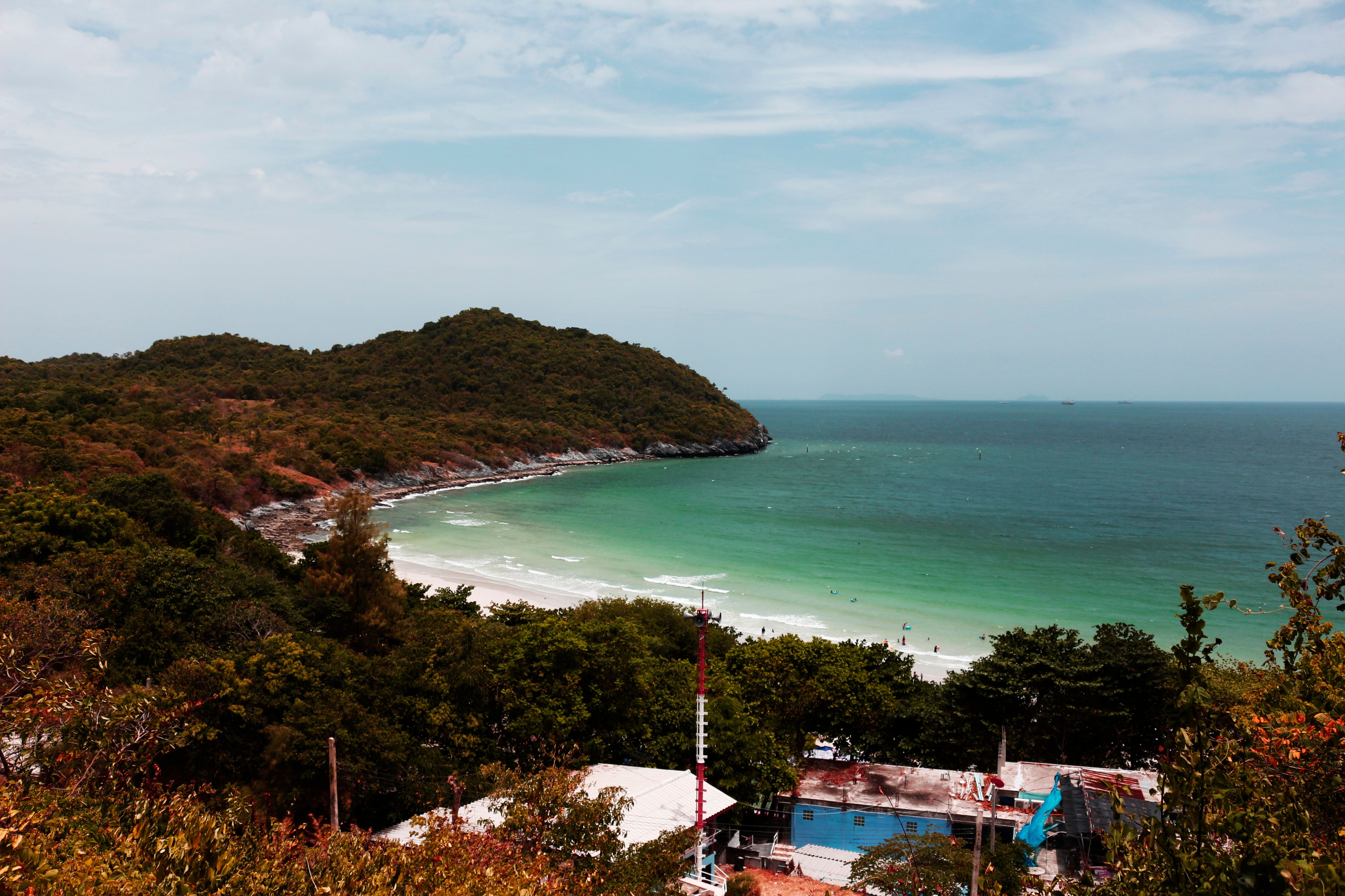A breathtaking view of a serene tropical beach surrounded by lush greenery and rolling hills.
