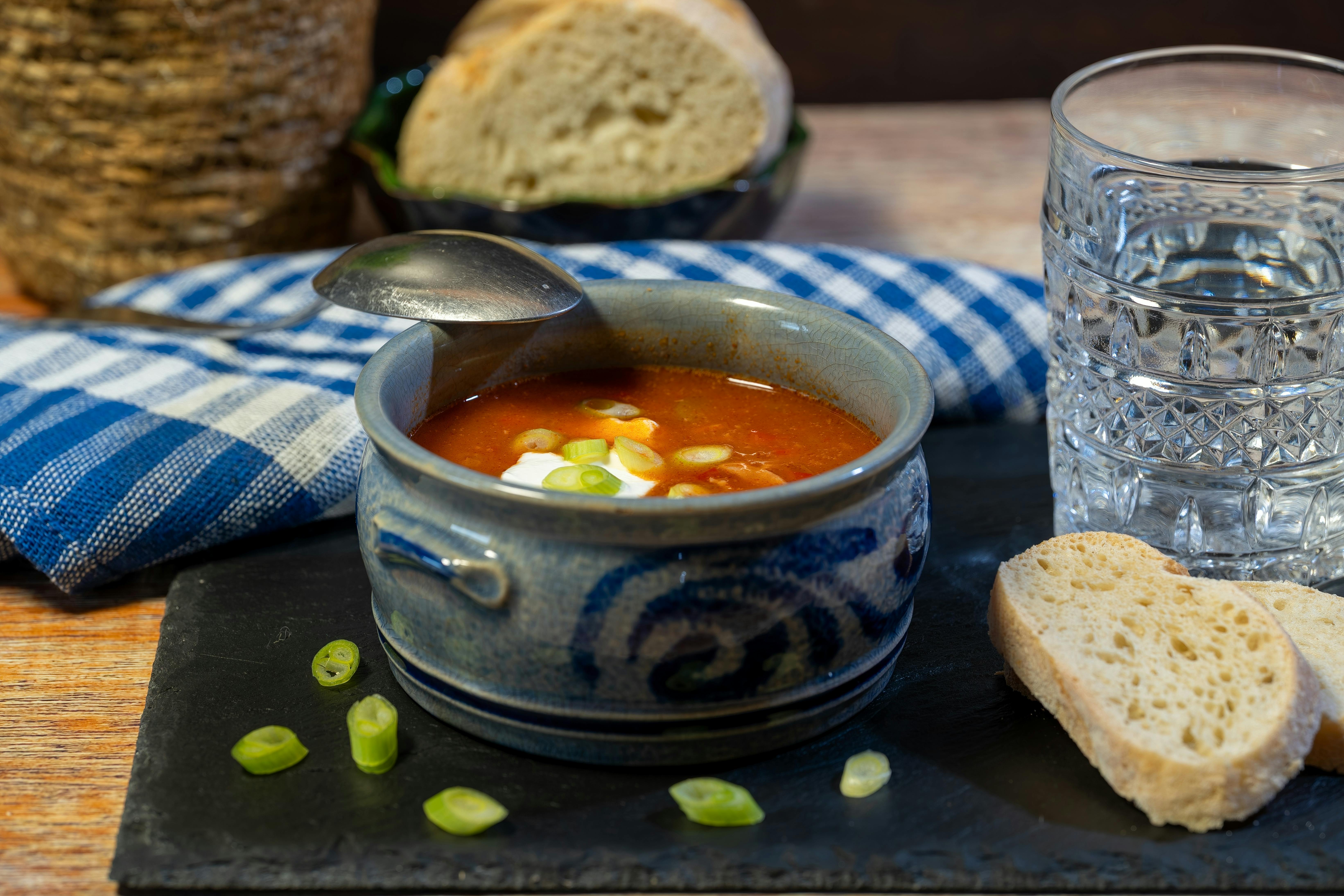 A bowl of classic solyanka soup, served with fresh bread and a glass of water.