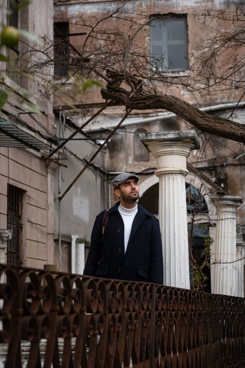 Free A stylish man stands amidst historic architecture outdoors, gazing thoughtfully. Stock Photo