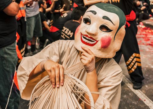 Free A person wearing a traditional mask at a vibrant outdoor cultural festival. Stock Photo