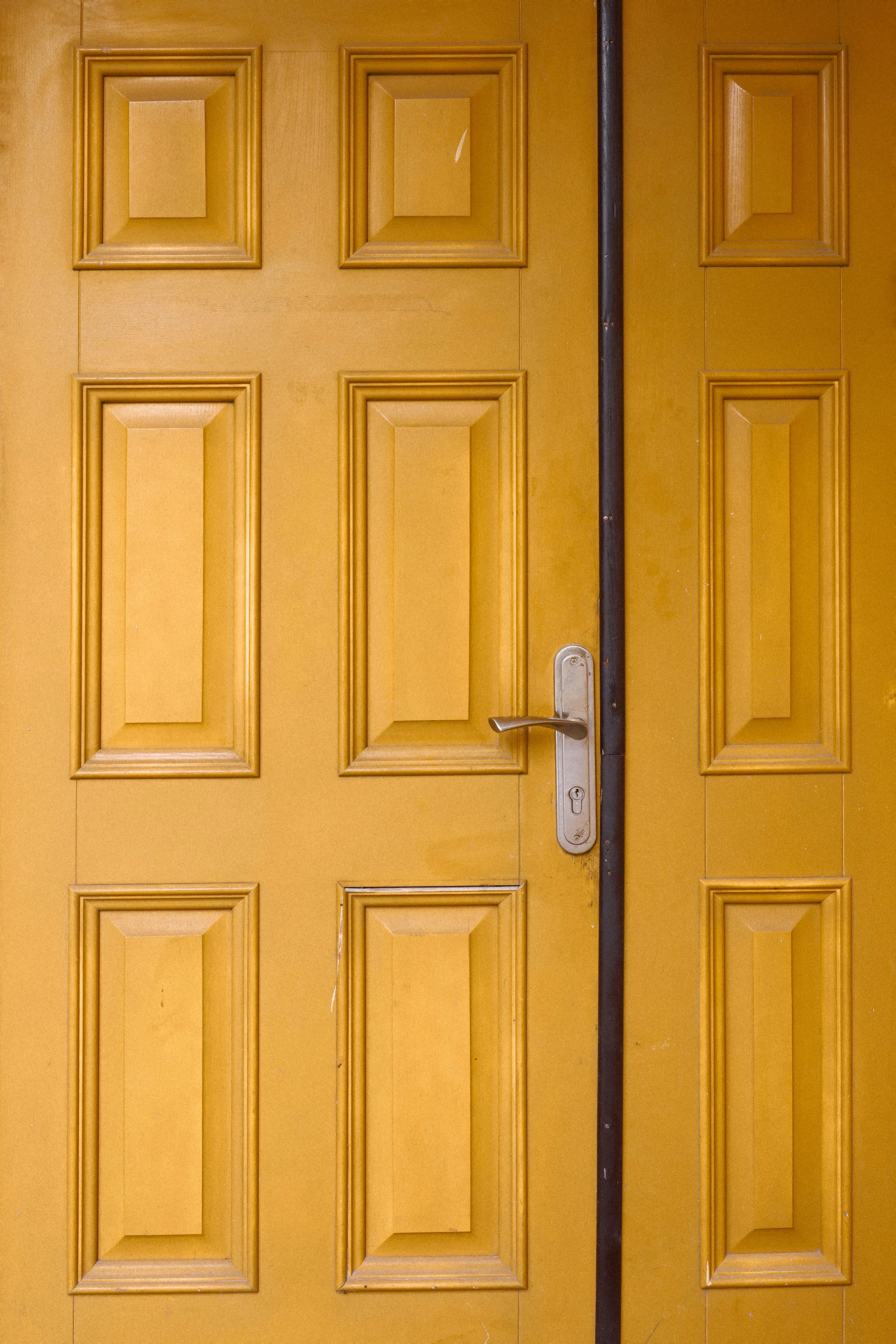 Vibrant yellow wooden door with panel details and a metal lock handle.