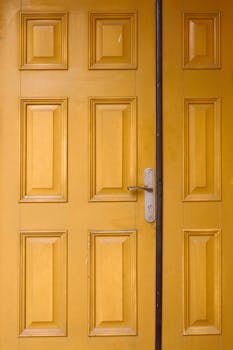 Vibrant yellow wooden door with panel details and a metal lock handle.