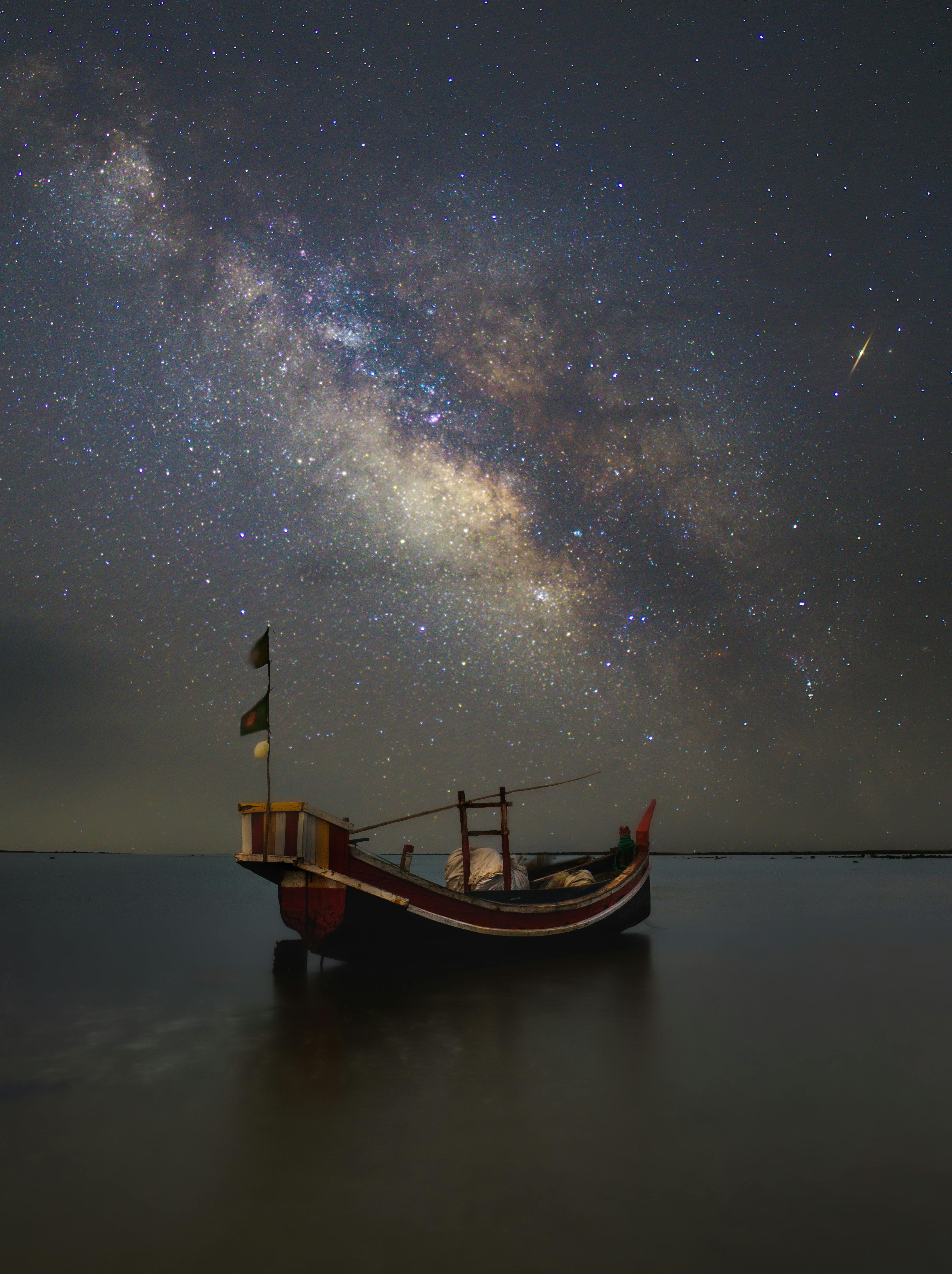 Captivating view of a boat under the Milky Way galaxy in Bangladesh. Perfect for night sky enthusiasts.