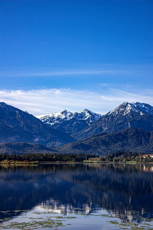 Free Majestic winter landscape with blue sky and clear lake reflections of snow-capped mountains in the Alps. Stock Photo