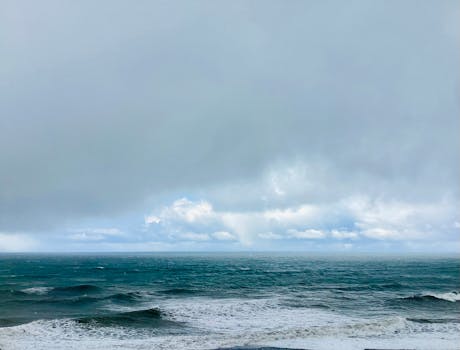 Vast ocean with waves under a cloudy sky, showcasing nature's serene beauty.