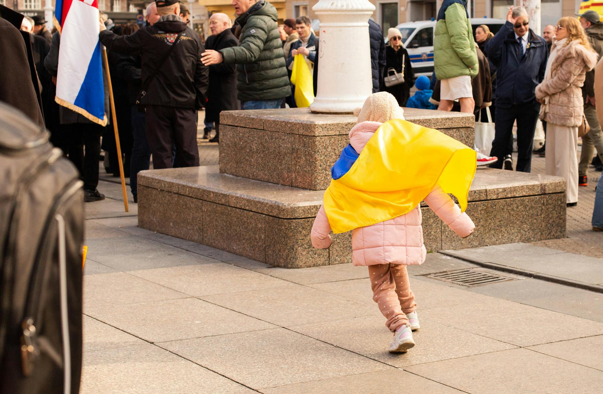 A child in Zagreb participates in a rally, holding a Ukrainian flag for peace and solidarity.