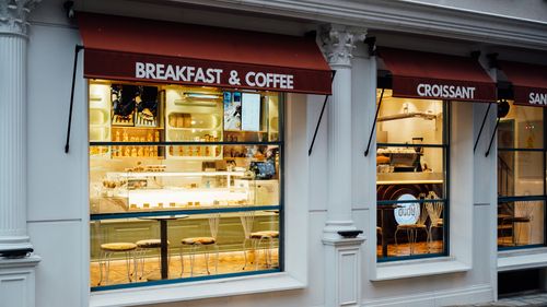 Free A cozy café with inviting window displays offering breakfast and coffee. Perfect for a morning treat. Stock Photo