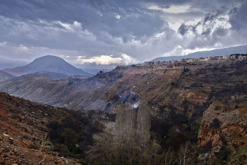 Dramatic view of Imouzzer Marmoucha with mountains and village under cloudy skies.
