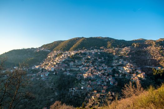 Explore the charming hillside village of Lagkadia, Greece, bathed in warm sunset hues.
