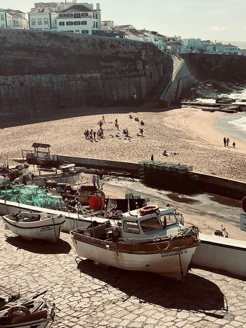 Free Fishing boats near a cliffside beach with people enjoying sunny outdoors. Stock Photo