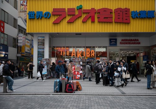 Crowds with luggage at Akihabara Radiokaikan, Tokyo, a hub for electronics and pop culture.
