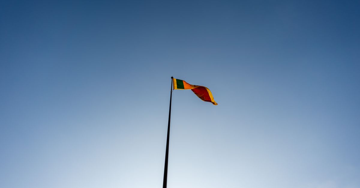 A majestic view of the Sri Lankan flag waving against a clear blue sky in Colombo.