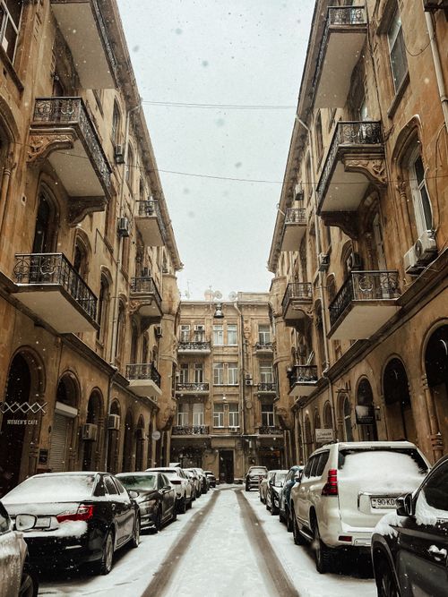 Free A serene snowy view of a classic street in Baku, showcasing parked cars and historical buildings. Stock Photo
