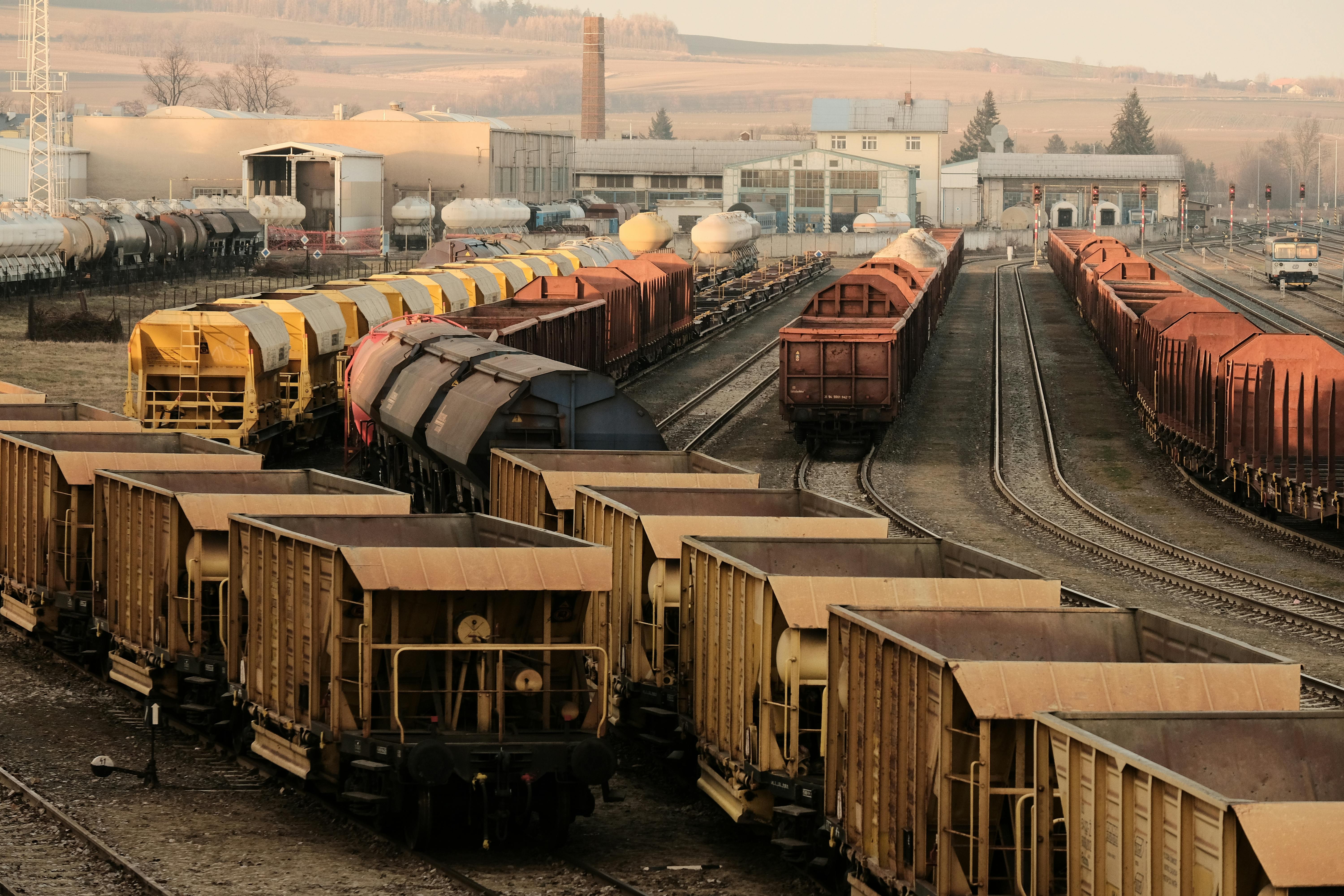 A busy freight train yard with multiple tracks and a variety of train cars in a rural setting.