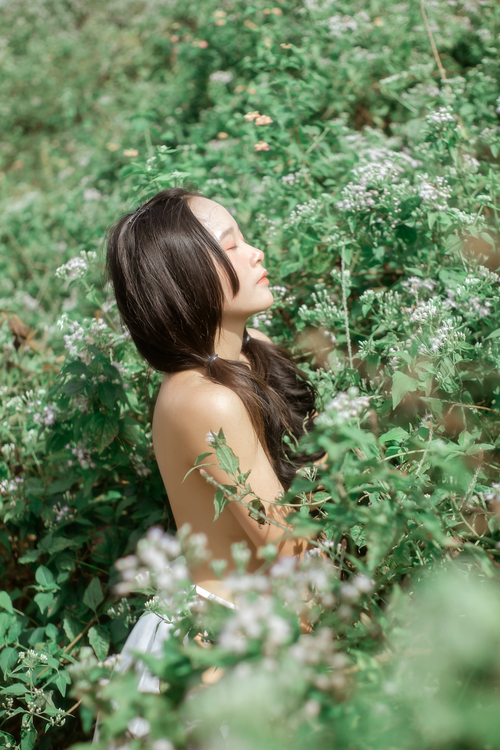 Free Woman enjoying tranquility among lush green foliage with eyes closed, serene and peaceful atmosphere. Stock Photo