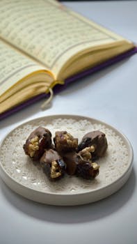 Close-up of chocolate-covered dates on a plate with an open Quran in the background, symbolizing Ramadan.