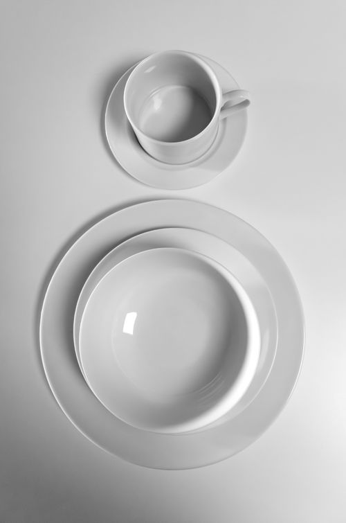 Free Elegant minimalist arrangement of white ceramic plates and coffee cup on a flat surface. Stock Photo