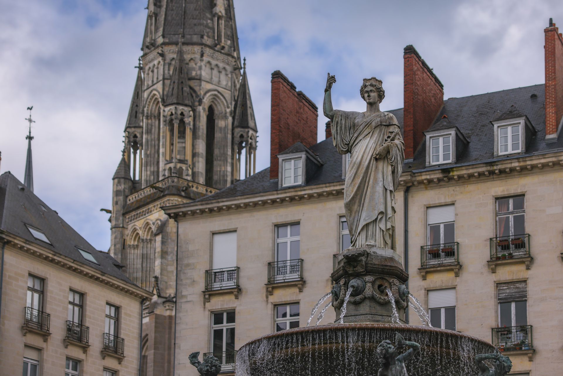 Elegant fountain and historic church facade in Nantes, France.