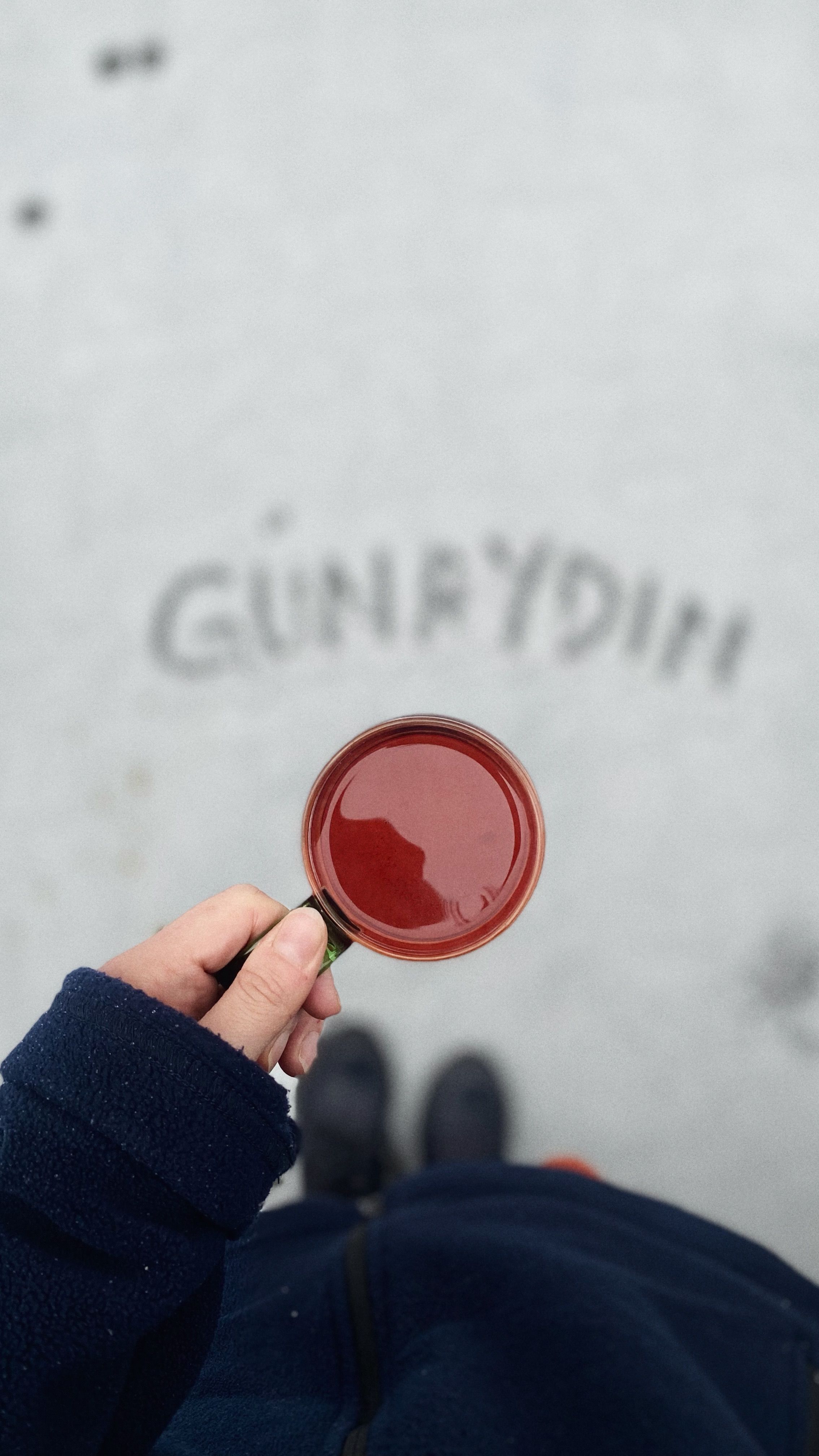 Hand holding coffee cup with 'Good Morning' written in sand.