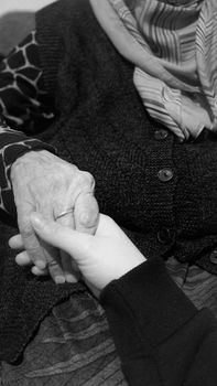 A touching black and white photo showing generational connection through a hand-holding gesture.