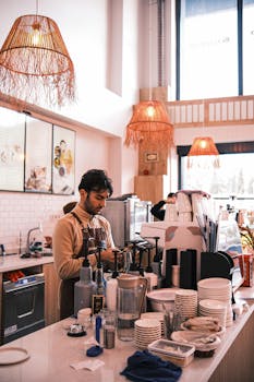 Barista preparing coffee in a warmly lit modern cafe with wicker lighting.