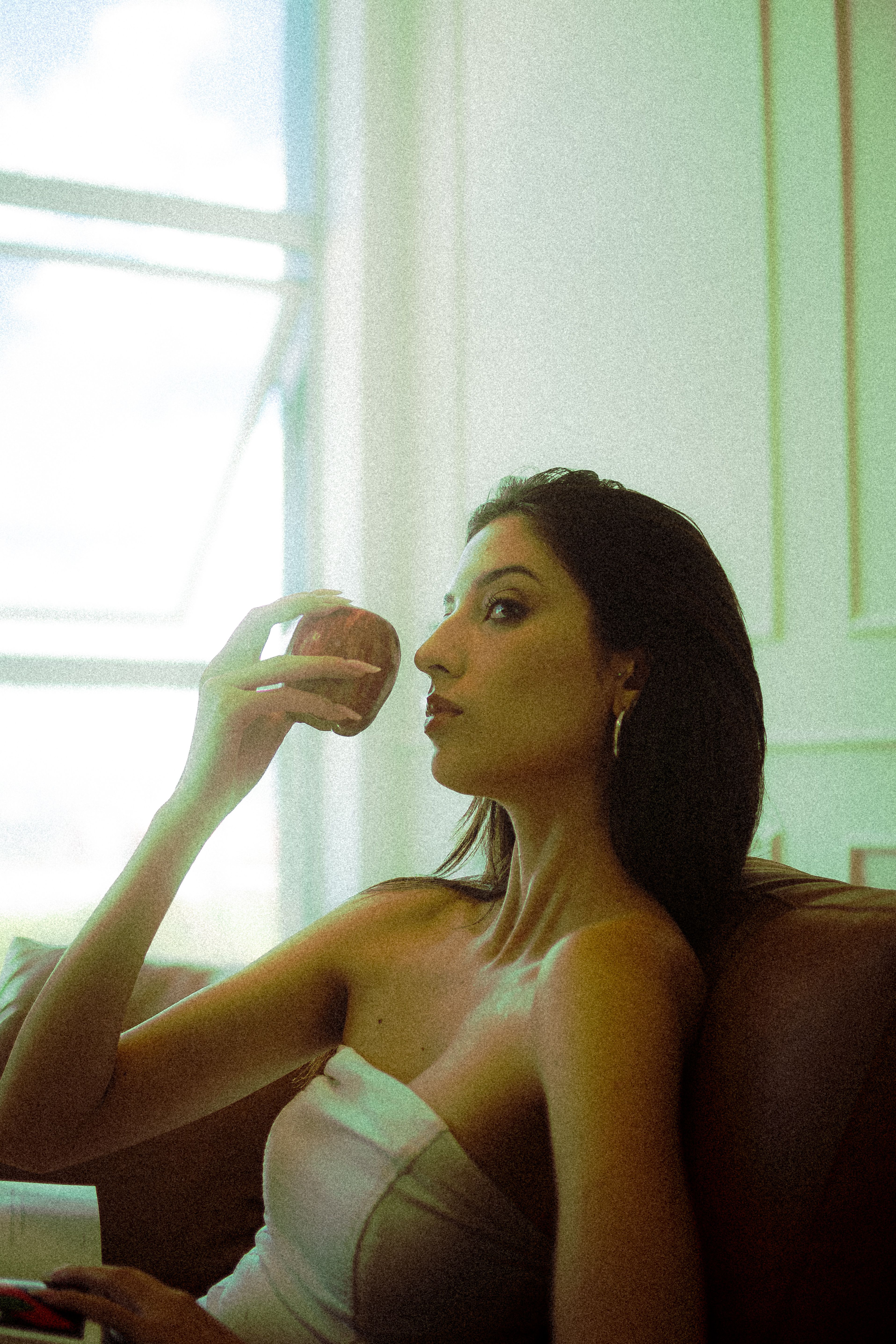 A woman in a serene indoor setting holding an apple, exuding elegance and tranquility.