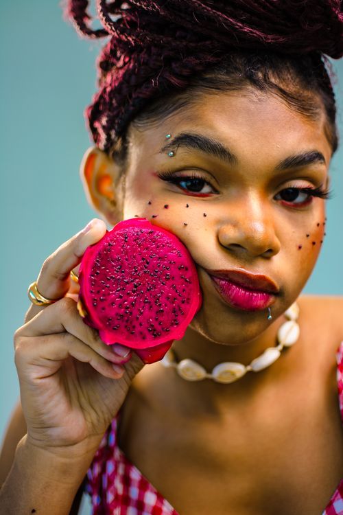 Free Teen girl with dragon fruit, adorned with bold makeup and jewelry, showcasing fresh, colorful vibes. Stock Photo