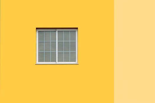 Clean and bright facade with a central white window on a vibrant yellow wall