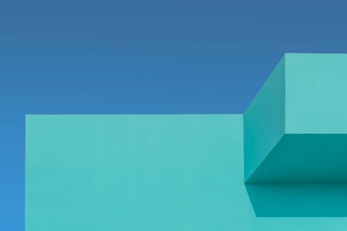 Free A minimalist turquoise building facade set against a vibrant blue sky, showcasing geometric architecture. Stock Photo