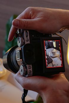 Close-up of photographer holding camera showing a table setting in the viewfinder.
