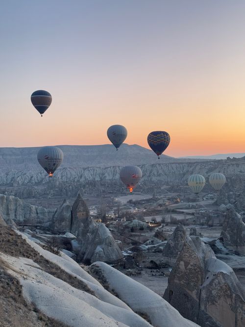 Free Scenic sunrise view of hot air balloons floating over Cappadocia's unique landscape. Stock Photo