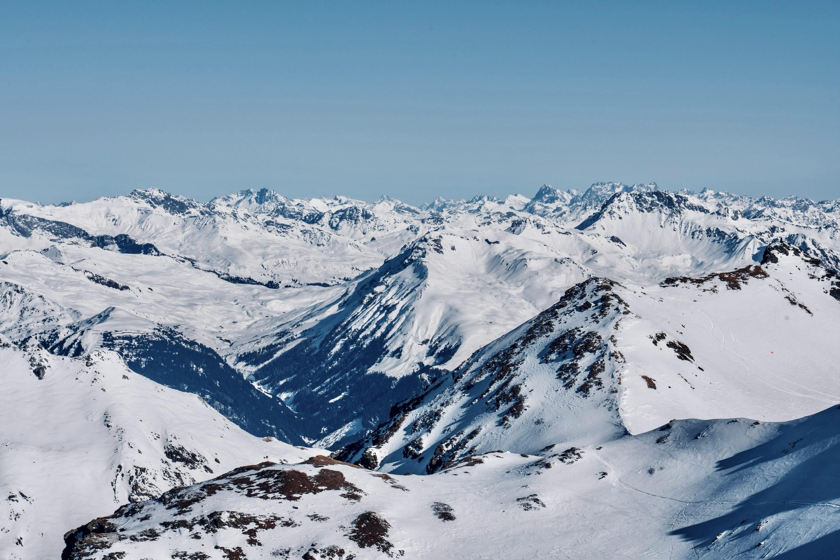 Snow-covered mountains stretching under a clear blue sky, emblematic of winter beauty.