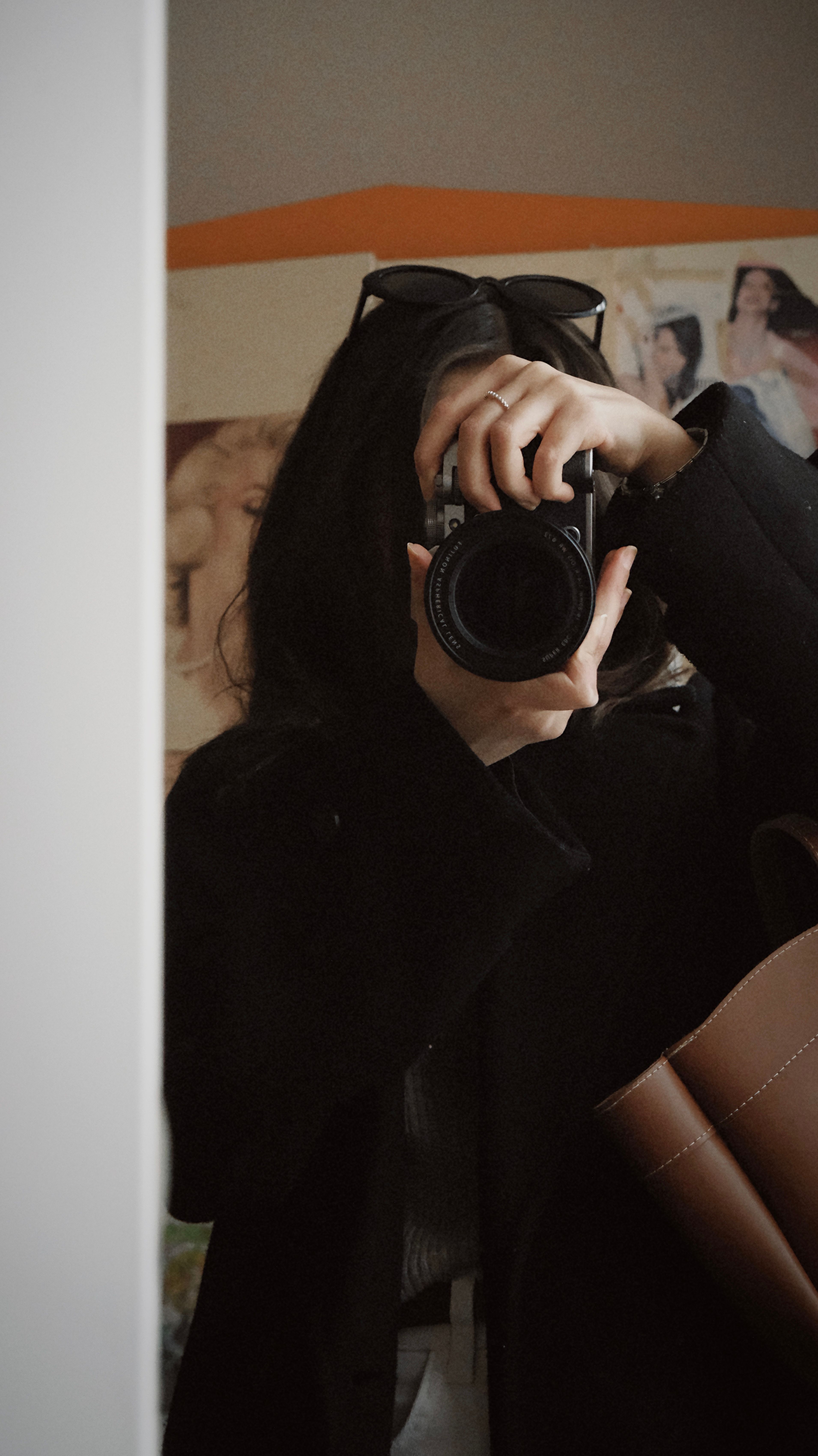 Artistic mirror selfie with a focus on camera capturing an anonymous photographer.