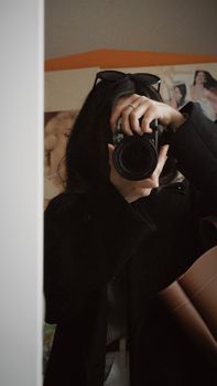 Artistic mirror selfie with a focus on camera capturing an anonymous photographer.