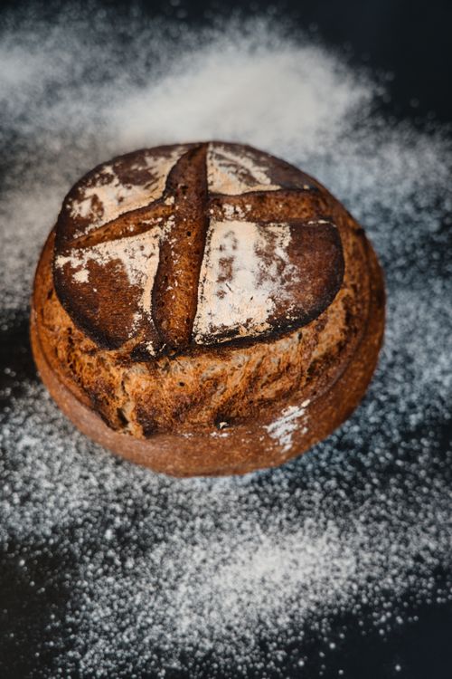 Free Close-up of a freshly baked round artisan bread loaf with a rustic look on a floured surface. Stock Photo