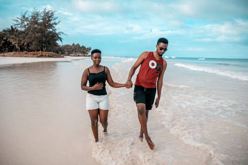 Photo of Couple Walking on Seashore While Holding Hands