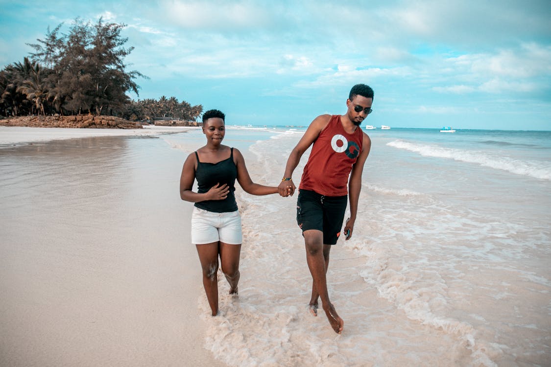 Photo of Couple Walking on Seashore While Holding Hands