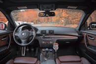 一辆豪华轿车的内部视图中，仪表板和方向盘映衬着秋天的背景