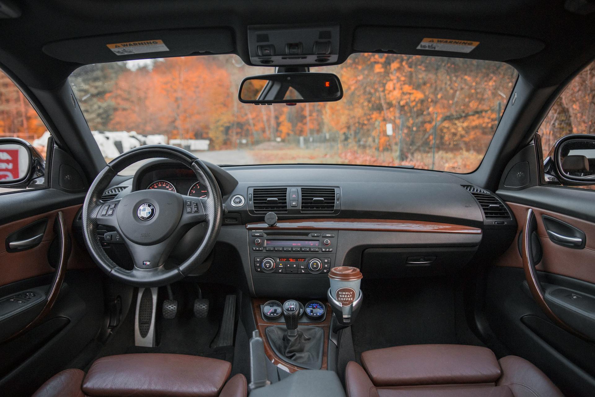 Interior view of a luxurious car showcasing its dashboard and steering wheel against a fall background.