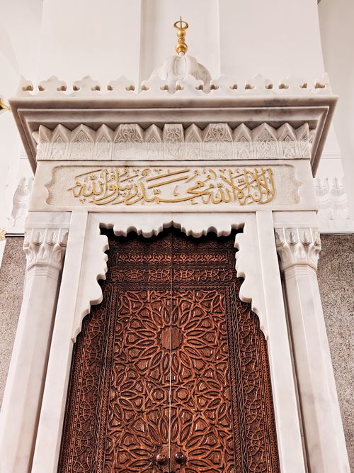 Free Beautifully carved wooden door with Arabic script in Islamic architectural style. Stock Photo